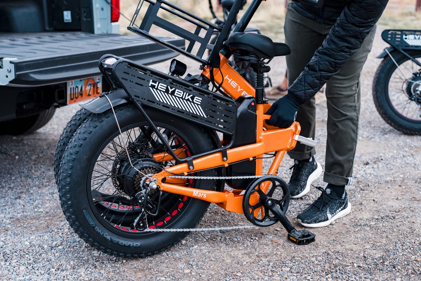 Compact folding utility e-bike with racks being handled next to a vehicle