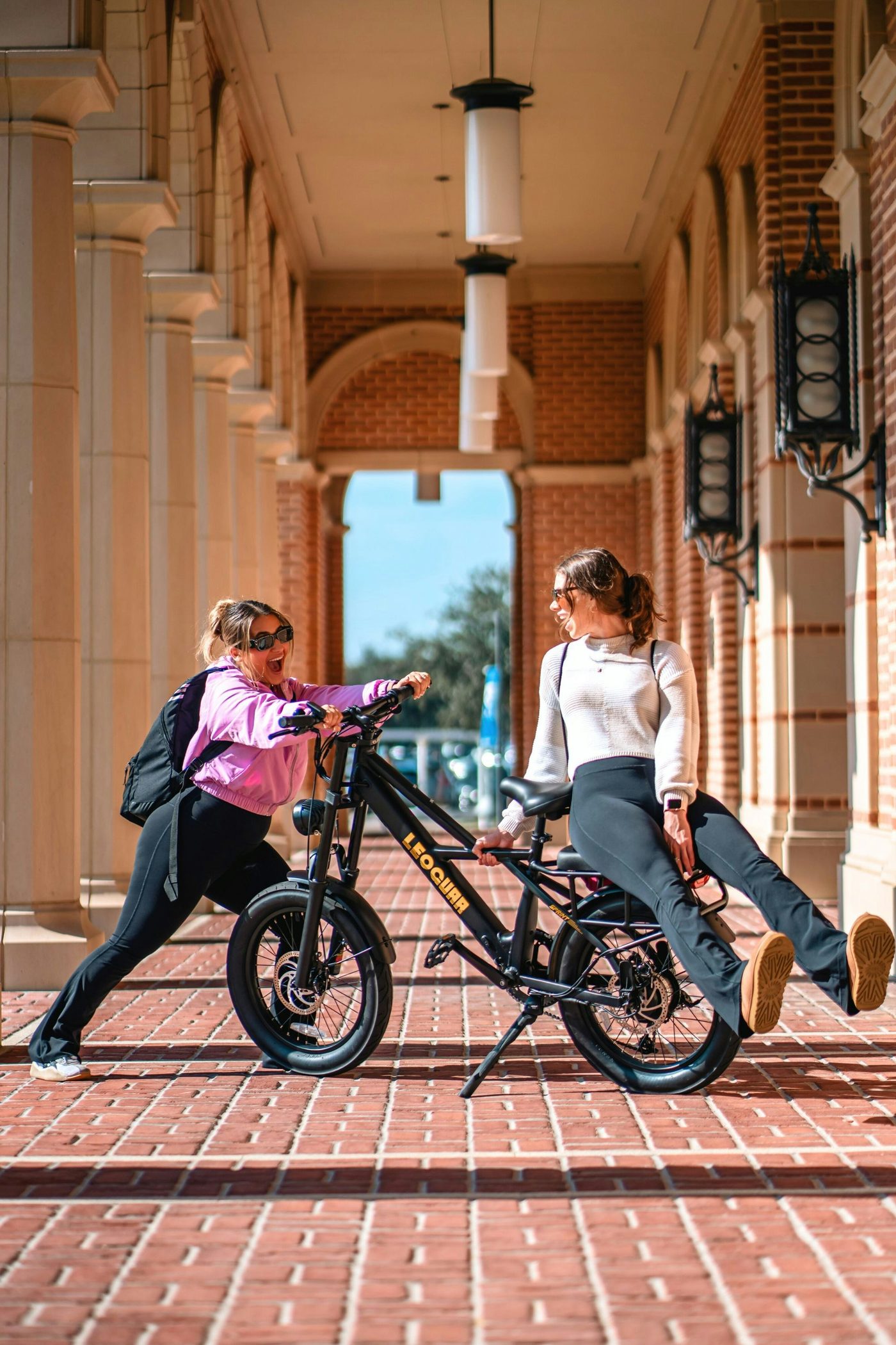 Two adults with a compact e-bike in a covered outdoor walkway