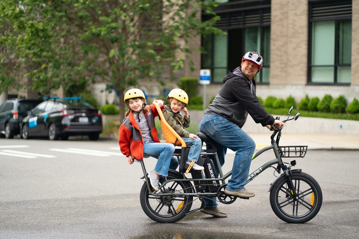 Adult carrying two children on an urban cargo e-bike